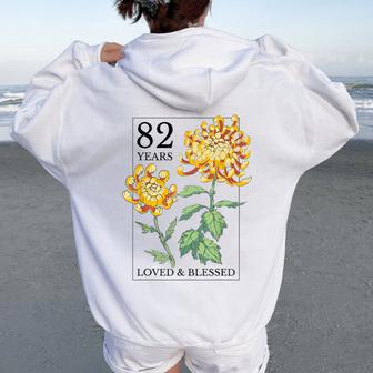 82 Years Loved And Blessed 花柄 フラワースタンプ 82歳の誕生日 レディース オーバーサイズ パーカー バックプリント - Kawaiitshirt
